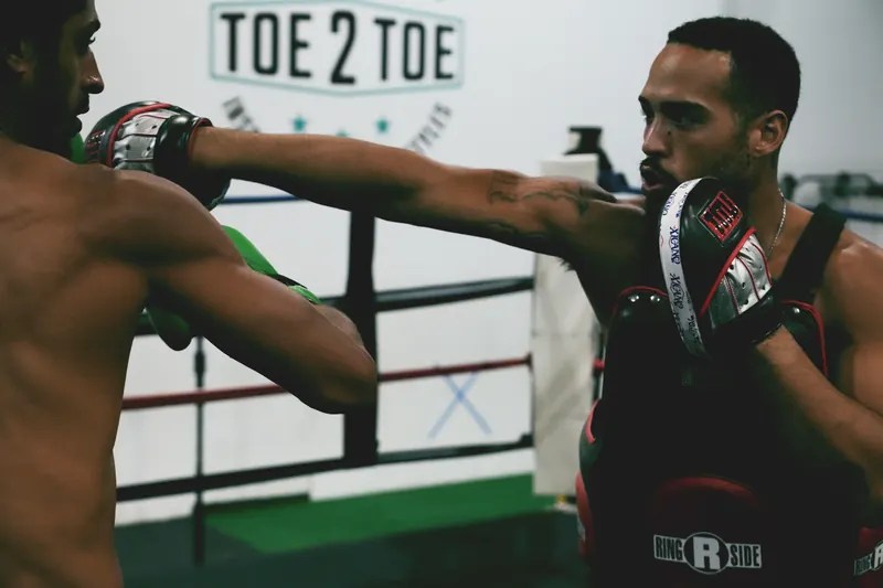 Jeremiah catching a punch on the mitts in front of the Toe 2 Toe logo